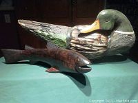 Photo showing both the wooden duck and fish sculptures, with duck painted green and brown and fish in natural wood finish