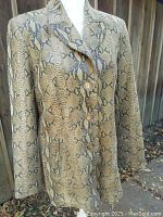 Full side and partial front view of the ladies' leather python print jacket on mannequin outdoors, showing the length, lapel collar and button closure.