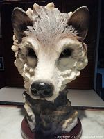 Front view of the resin wolf head sculpture showing detailed fur texture, eyes, and nose mounted on a wooden base.