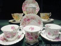 Six Royal Albert tea cups with matching saucers in various floral patterns arranged together for viewing.