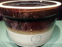 Side view showing the exterior glaze with a brown top, cream bottom, and blue heart number 2 marking.