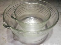 Two clear vintage glass mixing bowls nesting, showing pouring spouts and concentric etched ring design