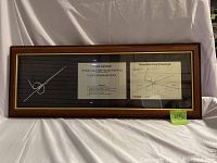 Full view of the framed parody artwork showing a coat hanger under glass with text and diagrams.
