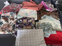 Assortment of fabric with floral, geometric, paisley and textured patterns in various colors folded on a black surface.