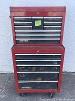 Front view of two-piece red Craftsman metal toolbox with multiple drawers. Upper section has smaller drawers, lower section larger drawers showing rust and wear.