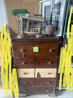 Photo of antique five drawer dresser with two bankers lamps and partridge lamp on top, visible condition including drawer damage and wear.