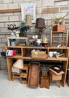 Photo showing the large wooden hutch filled with ceramic pitcher and jar set, two lamps, small artwork, wooden trays, crates, and stools beneath.