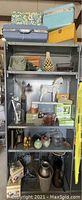 Full view of the shelving unit containing all items in the lot, showing cases on top shelves and various decorative items on lower shelves