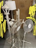 Six floor lamps and two floor fans positioned close together showing general condition and features