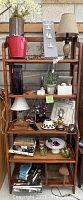 Full view of the 6 ft tall wooden folding shelf showing multiple shelves filled with home decor items including lamps, plants, glass vases, and picture frames.