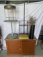 View of solid wood buffet with items arranged on top including vintage sweeper, metal stools, decorative racks, and vase with dried branches.