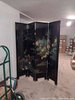 Full view showing all four black lacquered panels with multicolor nature-themed artwork, folding style and overall size in a basement room.