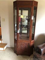 Front angle showing entire cabinet with glass top display and bottom wooden carved door with some wear visible.