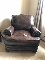 Front view of brown leather club chair showing seat, back, and armrest details.