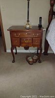 Pair of mahogany nightstands with brass drawer pulls and carved details, seen next to bed and with lamp on top