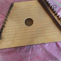 Front view of the wooden autoharp showing strings, tuning pegs, and central sound hole.