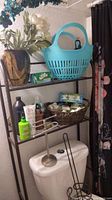 Bathroom shelf with vase, faux flowers, blue basket, towel holder, and various hair and styling products.