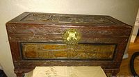 Full view of the antique carved camphor wood chest showing rectangular shape with carved borders and brass latch.