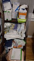 Photo of medical supplies stacked on a chair including boxed wound care bandages, gloves, and various catheters in packaging.