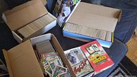 Photo of 5 boxes containing assorted sports cards including basketball, baseball, football and hockey cards, some loose and some stacked in boxes