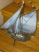 Full view of the stained glass sail boat showing marbled stained glass sails and metal rigging on wooden surface.