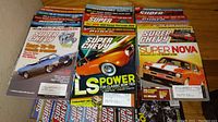 Top view of several Super Chevy magazines arranged side by side, showing colorful covers with Chevrolet Camaro, LS power features, and Super Nova focus.