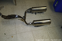 Top view of the twin chrome exhaust mufflers and pipes with visible surface wear and mounting bracket