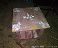 Photo of the square wooden child-sized table showing the hand painted unicorn face and floral decorations on the tabletop.