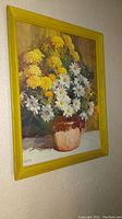 Frontal view of vintage floral print with bouquet of daisies and yellow flowers in yellow wooden frame.