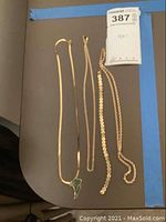 Overhead shot of all gold chains and pendant laid out on grey surface