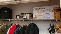 Multiple kitchen appliances on a closet shelf including Crockpot slow cookers and NuWave oven.