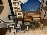 Wide shot showing multiple table and wall picture frames of various sizes and finishes stacked on floor.