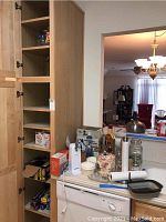 Kitchen counter with kitchenware including boxed sushi maker, can opener, blender box, food chopper, covered bowls, canisters, jars and rolls of foil and plastic wrap.