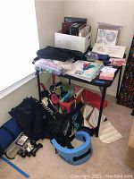 Photo showing assortment of items on and around a black table, including bags, workout mat, photo albums, scrapbooking supplies