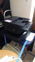 HP OfficeJet Pro 6978 printer on a table with touchscreen and paper tray visible.
