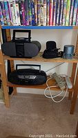 Sony ZS-S4IP black personal audio system and Panasonic RX-DS17 stereo on wooden shelf with VHS tapes above and surge protectors below.