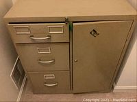 Front view of the metal filing cabinet showing three file drawers on the left and a lockable safe compartment on the right. Noticeable keyhole and combination lock on the safe door.
