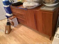 Front view of wooden server showing three drawers on left and double doors on right with items on top