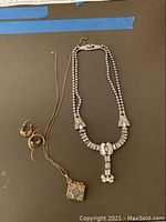 Full view of necklace, earrings, gold chain, and charm on display