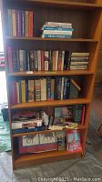 Full wooden bookshelf with assorted books including novels, RCMP books, and other titles.