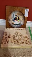 Photo of Royal Doulton 'The Old Balloon Seller' 3D character plate in wood wall mount and its original decorative box depicting street scene.