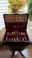 Photo of the entire silver-plated cutlery set in the open wooden canteen showing knives, forks, spoons, and serving pieces.