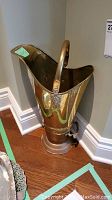 Angled side view showing the handle and shaping of the brass umbrella stand or hearth bucket-scuttle.