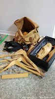 Photo showing wooden hangers, shoe forms in a black box, vintage iron, and canvas bag open with brushes.