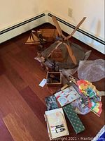 Wide angle shot showing glass topped carved wood table with multiple decorative items scattered around including carved wooden figures, wooden box, decorative fan, blank book, and wood boat model