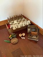 Overall lot showing the onyx chess set on a box, two small stone vases, floral pottery piece, and Swiss wood music box with detached horse.