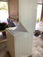 Side-front view of stacked unit in garage showing overall configuration and external condition