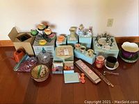Overview of assortment of candles, holders, PartyLite sets, and Princess House dish on floor.