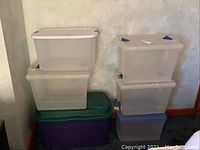 Photo showing six stacked translucent plastic storage bins with lids in white, blue, green, and purple colors.