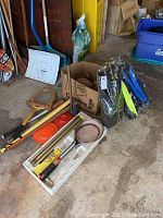 Photo showing assorted rackets, a baseball bat, frisbees, snorkel fins in various colors and a tire pump in a barn or garage environment